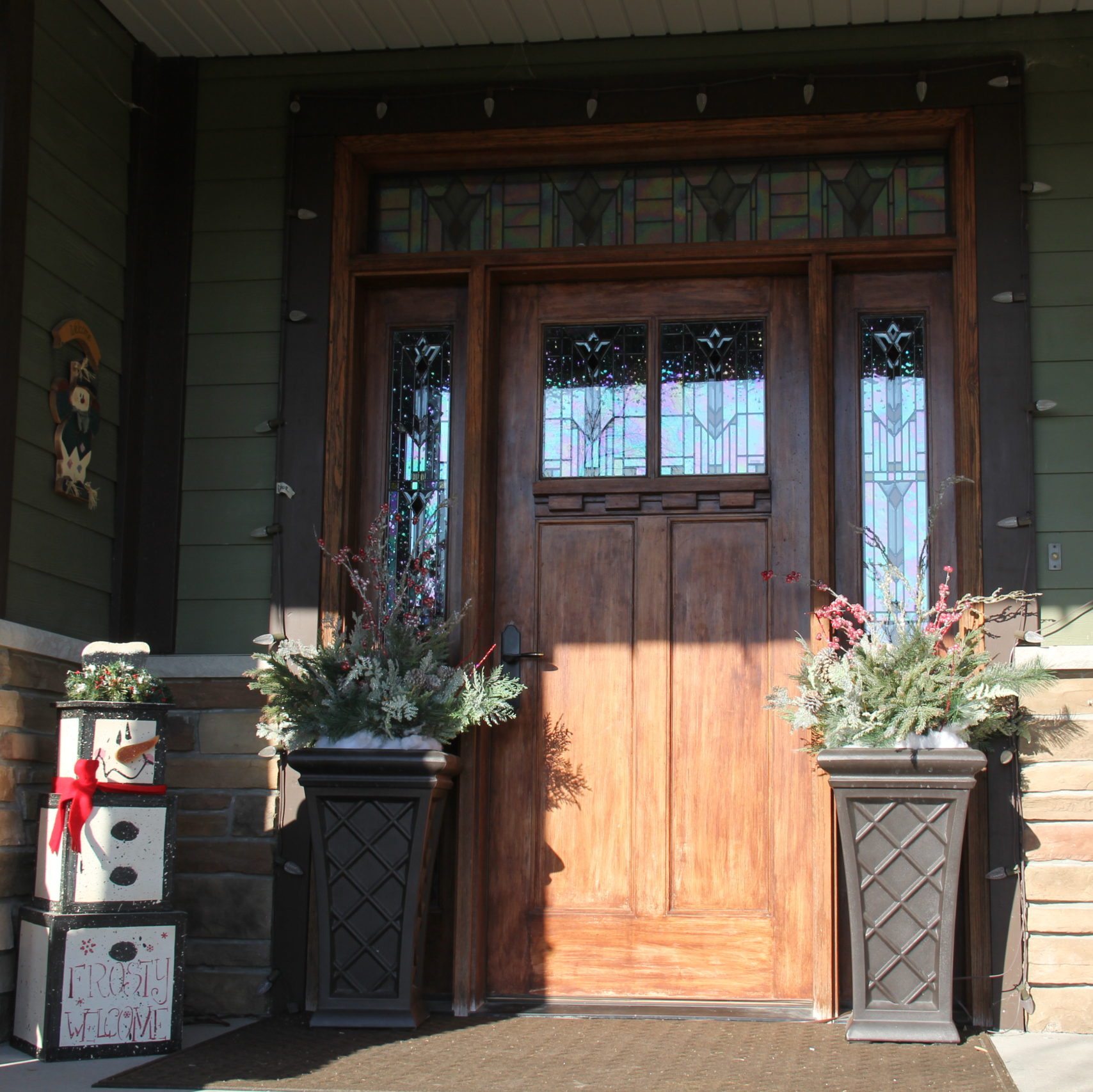 The front door gets bordered by lights with two tall planters and this year my snowman stack came outside as a greeter.