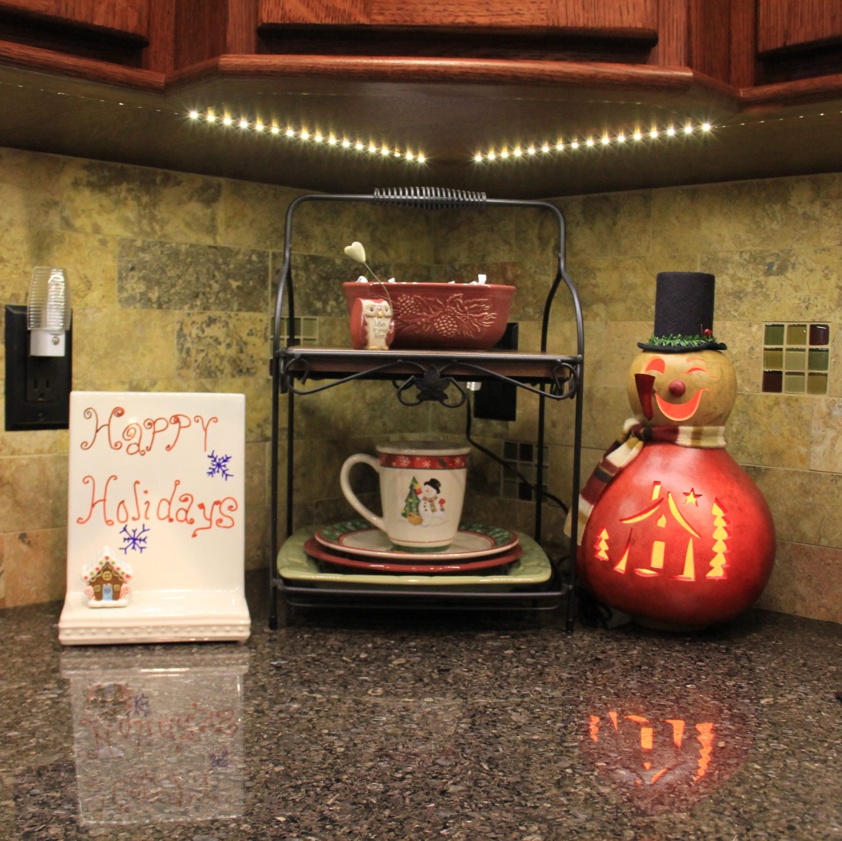 Cute little corner on my kitchen counter. Here the Longaberger wrought iron with dishes, the Nora Fleming memo board with cute gingerbread mini and the Meadowbrooke Gourd snowman all brighten the space.